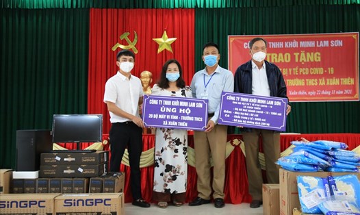 Đại diện lãnh đạo Công ty TNHH Khởi Minh Lam Sơn tặng quà cho trường THCS và trạm Y tế xã Xuân Thiên. Ảnh: NT