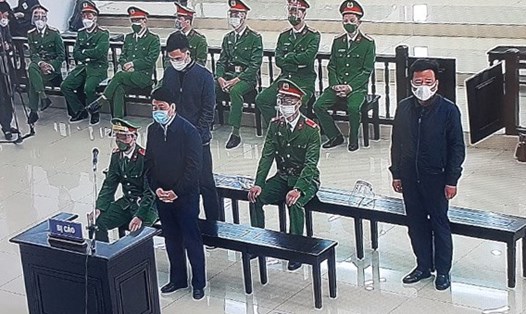Ông Nguyễn Đức Chung (đứng đầu) cùng hai bị cáo nghe toà tuyên án. Ảnh chụp qua màn hình.