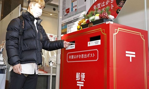 Một người bỏ thiệp chúc mừng năm mới vào thùng thư ở bưu điện Tokyo, Nhật Bản. Ảnh: Kyodo