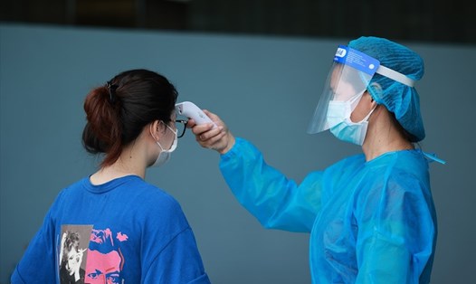 Cán bộ y tế đang đo thân nhiệt cho người dân trước khi vào khu vực tiêm vaccine COVID-19 Hà Nội. Ảnh: Hải Nguyễn