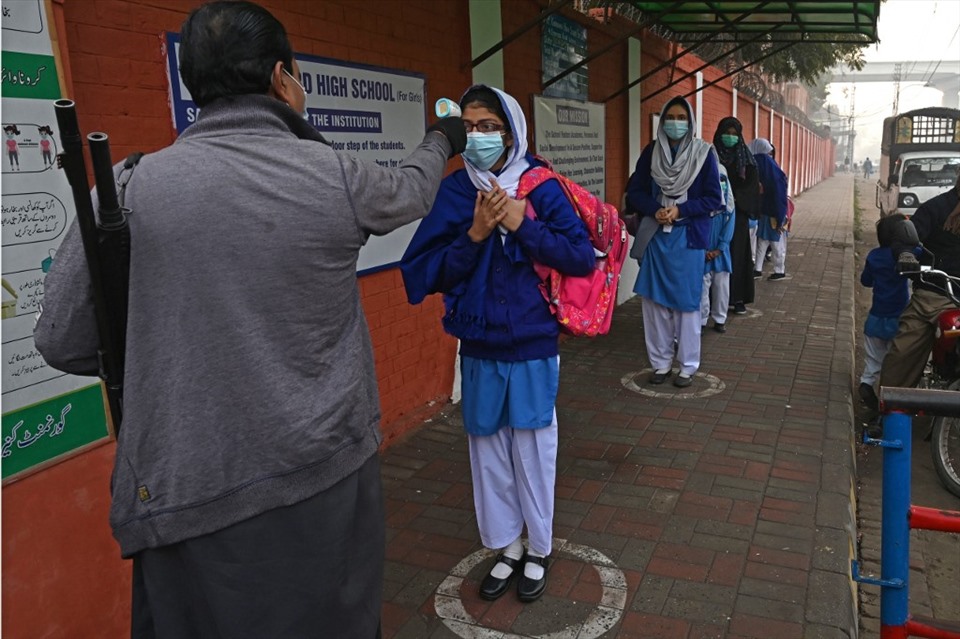 Nhân viên đo nhiệt độ học sinh tại một trường học ở Lahore, Pakistan, hôm 1.2 khi chính phủ mở lại các cơ sở giáo dục sau thời gian đóng cửa vì COVID-19. Ảnh: AFP.