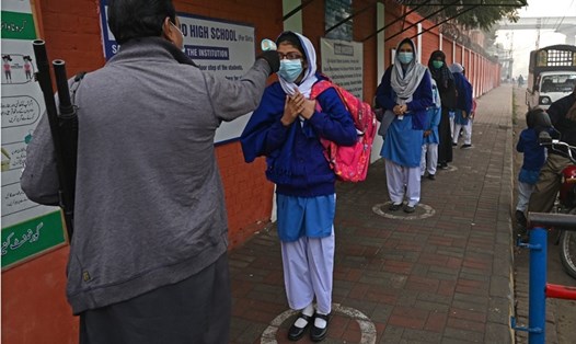 Nhân viên đo nhiệt độ học sinh tại một trường học ở Lahore, Pakistan, hôm 1.2 khi chính phủ mở lại các cơ sở giáo dục sau thời gian đóng cửa vì COVID-19. Ảnh: AFP.