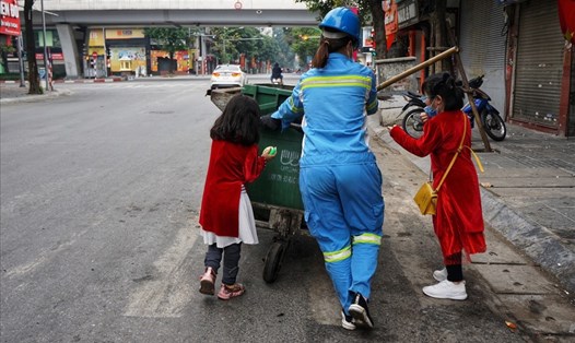 Chị công nhân vệ sinh cùng hai con gái trên phố Bạch Mai (Hà Nội) sáng mùng 1 Tết Tân Sửu. Ảnh: Nguyễn Huy Tú