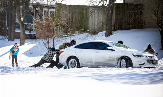 Người dân ở Austin, Texas, Mỹ, đẩy xe trên một đoạn đường tuyết phủ kín. Ảnh: AFP.