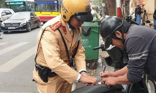 Cảnh sát giao thông Hà Nội lập biên bản với người vi phạm giao thông. Ảnh: CAHN.