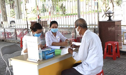 Cán bộ BHXH và bưu điện Việt Nam thực hiện chi trả lương hưu, trợ cấp BHXH cho người dân. Ảnh: Hà Anh