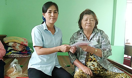 Chị Bích Tuyền (trái) trao sổ BHXH cho người tham gia BHXH tự nguyện. (Ảnh chụp trước thời điểm dịch COVID-19 bùng phát trở lại). Ảnh: Thanh Giang