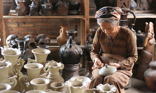 Bà Đàng Thị Phan bên những sản phẩm gốm Chăm làng Bàu Trúc. Ảnh: TRẦN ĐĂNG