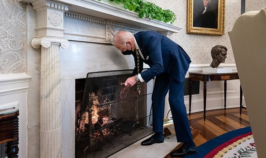 Tổng thống Joe Biden cho thêm củi vào lò sưởi trong Phòng Bầu dục hôm 22.1. Ảnh: Nhà Trắng
