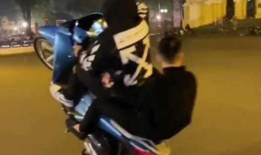 Hai thanh niên đi xe máy Honda SH không đội mũ bảo hiểm, còn bốc đầu xe máy đã bị xử phạt nghiêm khắc. Ảnh: Cắt từ clip.