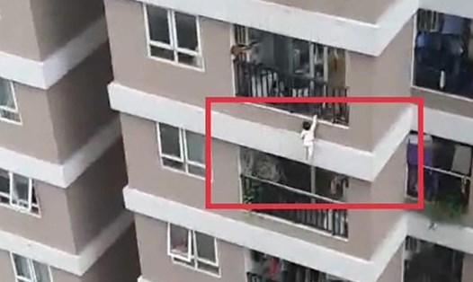 Hình ảnh cắt từ clip ghi lại cảnh bé gái trèo qua lan can, lơ lửng ở tầng 12A chung cư 60B Nguyễn Huy Tưởng.