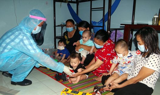 Lực lượng làm nhiệm vụ tại Khu cách ly trao đồ chơi trẻ em cho các em dưới 24 tháng tuổi tại khu cách ly tập trung. Ảnh: Văn Đông