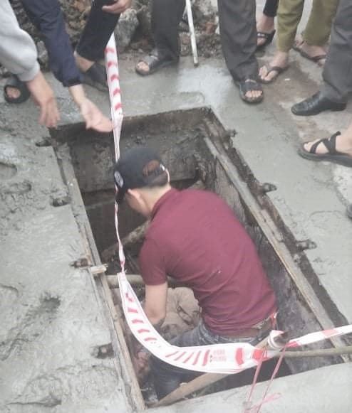 Người đi đường đang đưa chị X. dưới hố ga lên. Ảnh: Hue-S