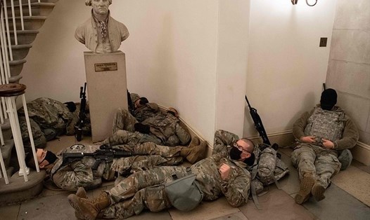 Lính Vệ binh Quốc gia Mỹ ngủ trên sàn của Điện Capitol ngày Hạ viện Mỹ họp hôm 13.1. Ảnh: AFP.