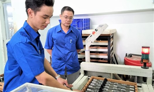 Công nhân Lại Trọng Ánh (bìa trái) và Giám đốc Bùi Đăng Hoàn, đang kiểm tra máy vệ sinh compac sợi con do anh Ánh 
sáng chế. Ảnh: Nam Dương