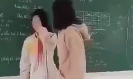 Nữ sinh B (bên phải ảnh) đánh bạn cùng lớp ngay trên bục giảng. Ảnh chụp video.