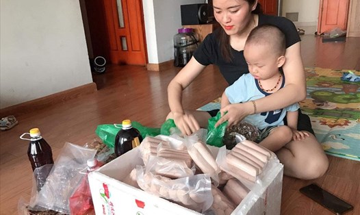 Chị Đỗ Thị Cúc (sống tại quận Long Biên, Hà Nội) vừa soạn hàng giao cho khách vừa trông con tại nhà.