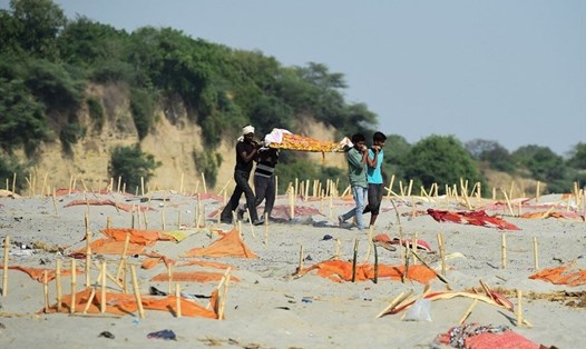 Gia đình đưa thi thi thể thân nhân là nạn nhân COVID-19 qua một bãi mộ nông ở bờ sông Hằng ở làng Shringverpur, Ấn Độ. Ảnh: AFP