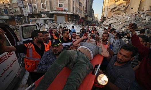 Người Palestine khiêng một người sống sót từ đống đổ nát của một tòa nhà sau cuộc không kích của Israel vào Gaza ngày 16.5. Ảnh: AFP.