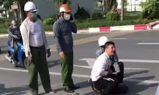 Đại uý Nguyễn Thanh Lâm (đội mũ bảo hiểm đỏ) vẫn đứng gọi điện thoại và nạn nhân Nguyễn Trần Minh sau khi vật lộn với tên cướp. Ảnh cắt từ clip.