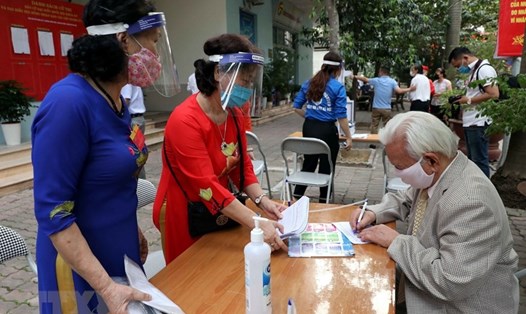 Hướng dẫn người dân khai báo y tế trước khi vào bầu cử ở khu vực bỏ phiếu số 4, phường Vĩnh Phúc, quận Ba Đình, Hà Nội. Ảnh: TTXVN