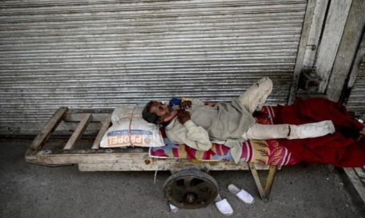Một người đàn ông nằm nghỉ trước một cửa hàng đóng cửa ở thủ đô New Delhi, Ấn Độ, ngày 23.5. Ảnh: AFP