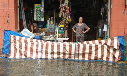 Người dân buôn bán trên đường Bạch Đằng (quận Bình Thạnh) phải dùng các tấm bạt lớn căng trước cửa ngăn nước tràn vô nhà. Ảnh: Minh Quân