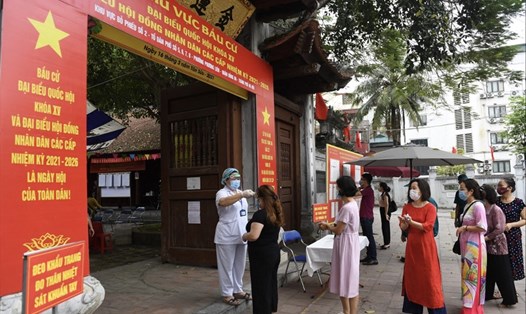 Đo thân nhiệt trước khi vào một điểm bầu cử ở Hà Nội ngày 23.5. Nguồn: AFP