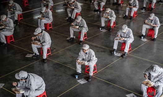 Công nhân một nhà máy Trung Quốc giữ khoảng cách xã hội trong giờ ăn trưa. Ảnh: AFP
