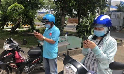 Người lao động Công ty Asuzac (Khu chế xuất Tân Thuận, TPHCM) khai báo y tế bằng điện thoại thông minh trước khi vào doanh nghiệp làm việc. Ảnh: Đức Long