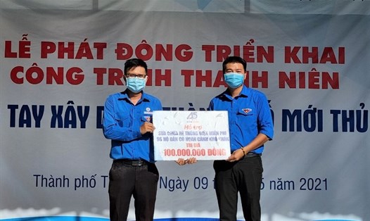 Ông Huỳnh Tấn Khương (bên trái), Bí thư Đoàn Thanh niên Cộng sản Hồ Chí Minh EVNHCMC trao biểu trưng hỗ trợ sửa chữa hệ thống điện miễn phí cho 90 hộ gia đình có hoàn cảnh khó khăn cho đại diện Thành đoàn Thành phố Thủ Đức. Ảnh Nam Dương