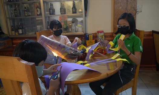 Em Lê Huỳnh Minh Khuê cùng các em đang làm kính chắn giọt bắn phòng chống dịch COVID-19. Ảnh: T.A