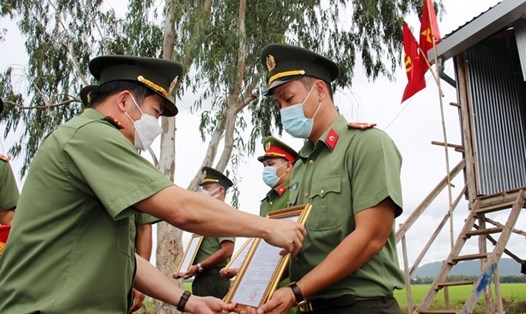 Đại tá Đinh Văn Nơi trao quyết định thăng cấp bậc hàm cho cán bộ, chiến sĩ đang ở các điểm chốt trực phòng chống dịch COVID-19. Ảnh: CAND