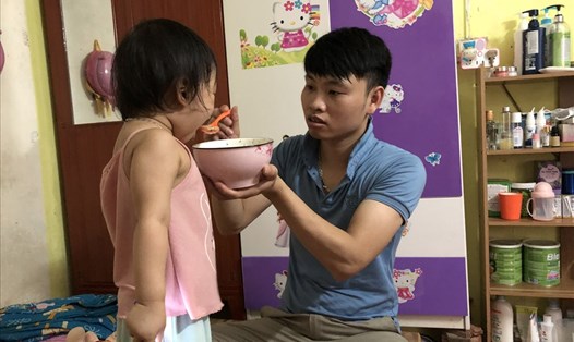Anh Nguyễn Văn Tâm đang cho con cái ăn cháo trong căn phòng trọ. Ảnh: Bảo Hân