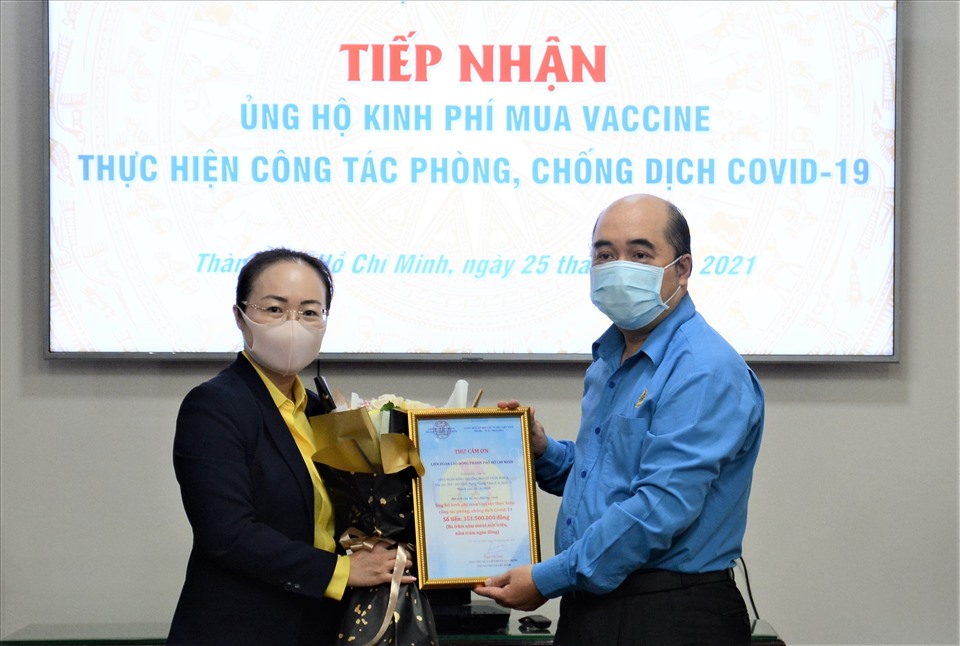 Phó Chủ tịch LĐLĐ TPHCM Hồ Xuân Lâm (bên phải) tiếp nhận biểu trưng số tiền do tập thể người lao động của Ngân hàng Nam Á ủng hộ mua vaccine phòng, chống dịch COVID-19. Ảnh LĐLĐ TPHCM