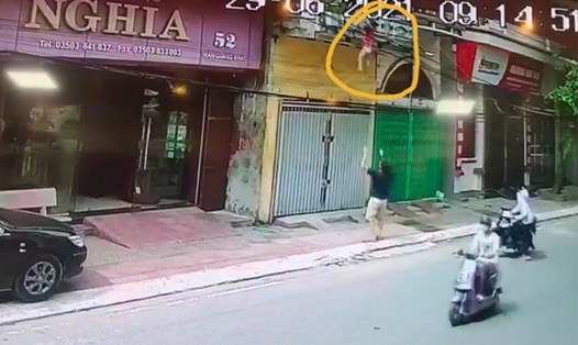 Bé gái 4 tuổi ở TP.Nam Định đánh đu trên lan can tầng 2 nhà mình trước khi rơi xuống đất và được người đàn ông đón, đỡ. Ảnh cắt từ clip.