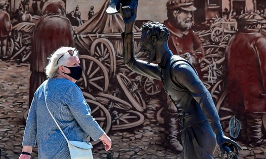 Một người phụ nữ đeo khẩu trang đi ngang qua một tác phẩm điêu khắc ở Serpukhov, cách Mátxcơva, Nga, khoảng 95km. Ảnh: AFP