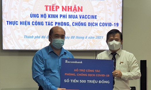 Đại diện Sacombank (bên phải) trao 500 triệu đồng để hỗ trợ mua vaccine phòng COVID-19 cho người lao động. Ảnh: Đức Long