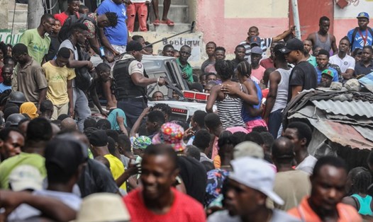 Đám đông theo dõi 2 người đàn ông bị cáo buộc liên quan đến vụ ám sát Tổng thống Jovenel Moise trên xe cảnh sát ở Port au Prince. Ảnh: AFP