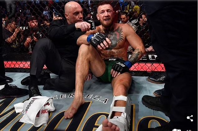 Conor McGregor ngồi bệt xuống sàn đấu, chấp nhận thua Dustin Poirier sau khi bị vỡ mắt cá chân ở cuối hiệp 1. Ảnh: Daily Mail.