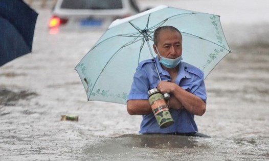 Người dân ngâm mình trong dòng nước vì đường phố biến thành sông ở Trịnh Châu, Hà Nam. Ảnh: Xinhua
