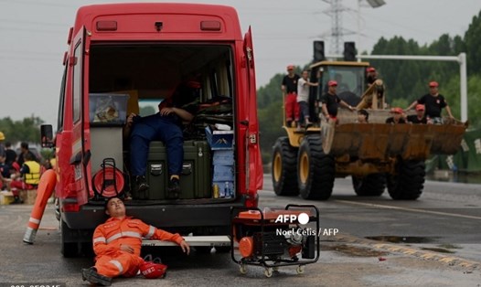 Các nhân viên cứu hộ nghỉ ngơi phía sau xe tải. Ảnh: AFP
