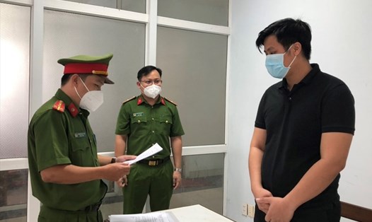 Cơ quan cảnh sát điều tra Công an Đà Nẵng đọc quyết định khởi tố bị can, tạm giam Nguyễn Lâm Mạnh (áo đen). Ảnh: Công an