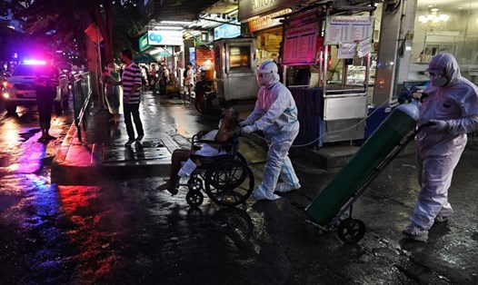Bệnh nhân COVID-19 cao tuổi ở Bangkok, Thái Lan, được đưa ra khỏi nhà để y bác sĩ tiếp tục điều trị thêm ở bệnh viện. Ảnh: AFP