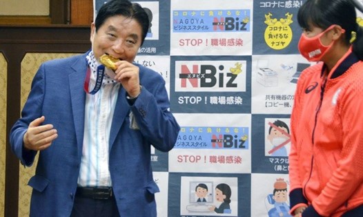 Thị trưởng thành phố Nagoya ông Takashi Kawamura kéo khẩu trang và cắn tấm huy chương vàng Olympic Tokyo 2020 gây tranh cãi. Ảnh: KyodoNews