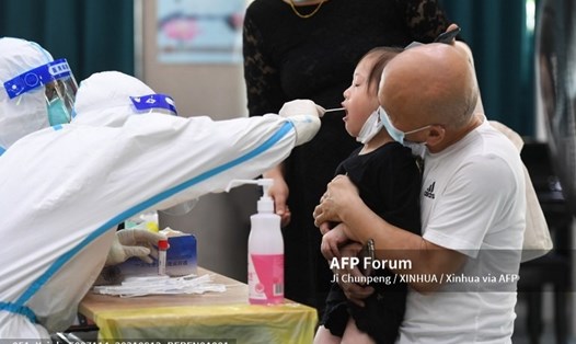 Một nhân viên đang lấy dịch hầu họng của một bé gái. Ảnh: AFP
