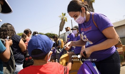 Nhân viên y tế phân phát đồ dùng học tập, khẩu trang, tiêm chủng vaccine COVID-19 cho trẻ em trong một sự kiện tựu trường ở Los Angeles, Mỹ. Ảnh: AFP