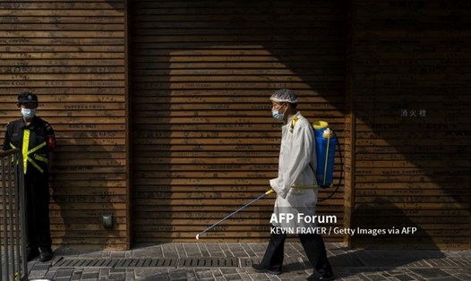 Một công nhân xịt chất khử trùng để ngăn ngừa sự lây lan virus gây bệnh COVID-19 tại một khu mua sắm ở Bắc Kinh, Trung Quốc. Ảnh: AFP