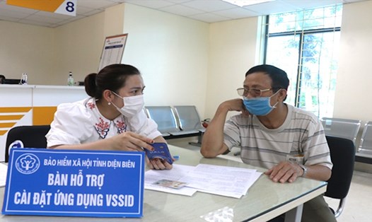 Cán bộ BHXH tỉnh Điện Biên hướng dẫn phụ huynh học sinh cài đặt ứng dụng VssID-BHXH số. Ảnh: BHĐB