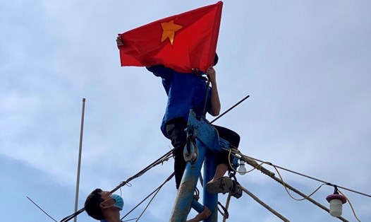 Cán bộ công đoàn huyện Diễn Châu treo cờ Tổ quốc động viên người lao động trong mùa dịch bệnh. Ảnh: VDT